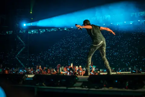 Enrique Iglesias señala al público desde la pasarela bajo un haz de luz. Enrique Iglesias · Granca Live Fest, Gran Canaria, julio 2025