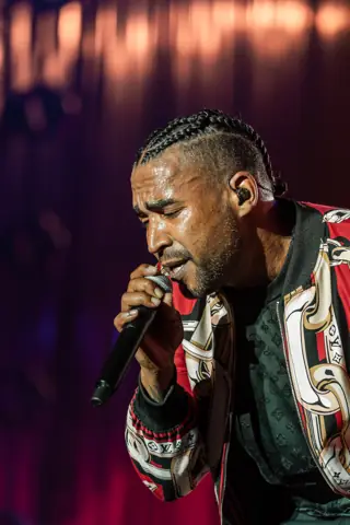 Don Omar canta con los ojos cerrados bajo luz roja. Don Omar · Cook Music Fest, Tenerife, julio 2026