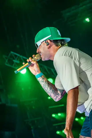 Feid con gorra verde canta al micrófono. Why Agency Granca Live Fest Feid, Gran Canaria, julio 2025