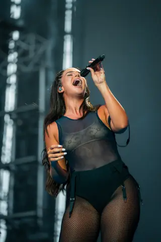 Nathy Peluso canta con el micrófono en alto bajo luz azul. Why Agency Granca Live Fest Nathy Peluso, Gran Canaria, julio 2025