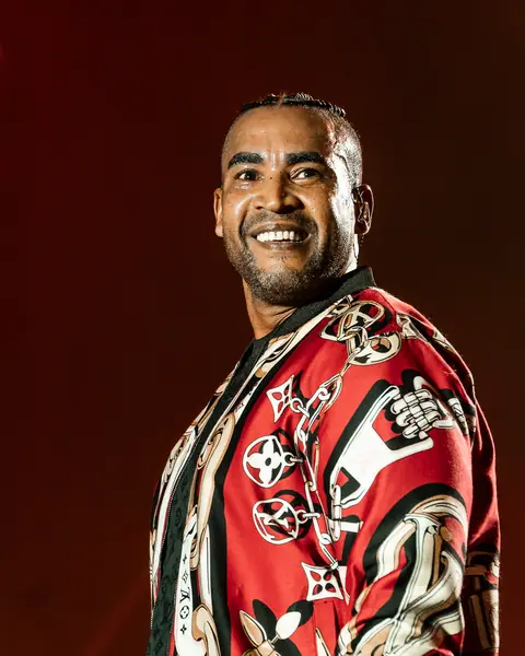 Don Omar smiles in a red patterned jacket under warm light. Cook Music Fest, Tenerife, July 2026.
