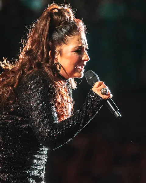Gloria Estefan sings into the microphone under warm light. Cook Music Fest, Tenerife, July 2025.