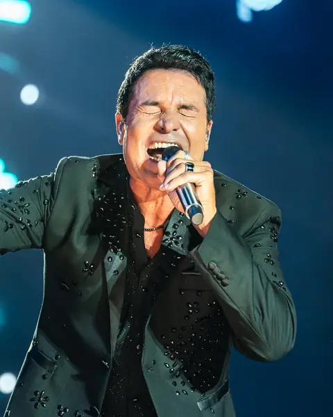 Chayanne sings into the microphone with his arm out under blue light. Cook Music Fest, Tenerife, July 2026.