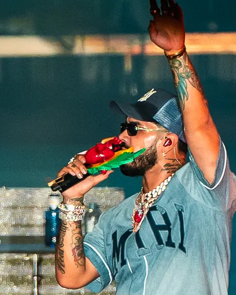 Anuel AA sings into the microphone under blue light. Reggaeton Beach Festival, Tenerife, June 2024.