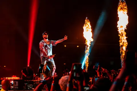 Anuel AA with open arms between two columns of fire. Reggaeton Beach Festival, Tenerife, June 2024.