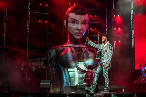 Jason Derulo beside the giant robot statue of his stage. Granca Live Fest, Gran Canaria, July 2025. Photo for Why Agency.