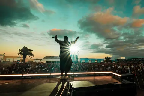 Silueta de Orishas en el escenario al atardecer ante el público. Lava Live, Lanzarote, junio 2025. Foto para Why Agency.