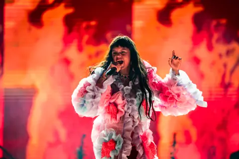 Bomba Estéreo under red light in a flower dress. Granca Live Fest, Gran Canaria, July 2025. Photo for Why Agency.