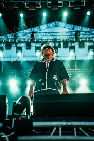 Beéle canta con gorra en el escenario bajo luz azul. Cook Music Fest, Tenerife, julio 2025.