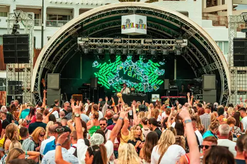 Escenario en arco con pantalla verde y público con las manos arriba. 90s Baby, Tenerife, mayo 2025