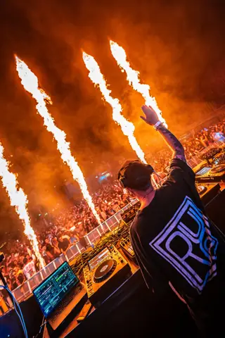 DJ con la mano en alto entre llamaradas sobre el público. Criterio by Wade, Gran Canaria, mayo 2024