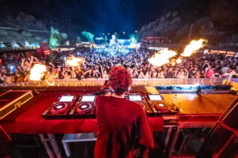 DJ de espaldas en la cabina, llamaradas y miles de personas de noche. La Misa, Gran Canaria, marzo 2024