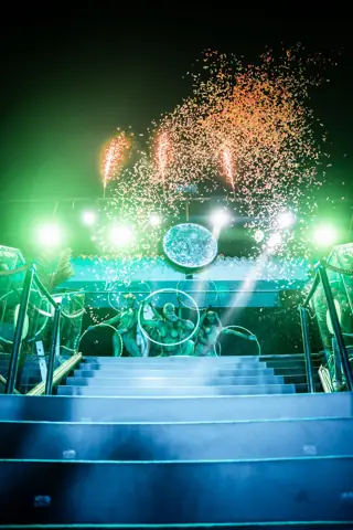 Escalinata iluminada en verde, bailarinas con aros y cañones de confeti. Papagayo Beach Club, Tenerife, octubre 2026
