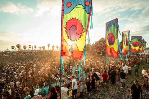 Público y escenario al atardecer, con banderas y luz dorada. elrow Tenerife XXL, octubre 2026
