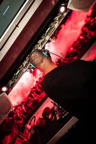Jordi Sanz de espaldas en cabina, con la pista teñida de rojo y humo. Papagayo Beach Club, Tenerife, marzo 2026