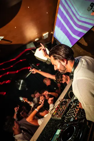 DJ sonriente con el dedo en alto sobre el público desde la cabina. Moovin, Tenerife, septiembre 2025