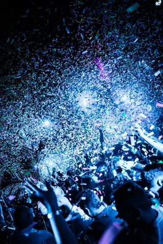 Lluvia de confeti azul sobre las manos del público en la oscuridad. Papagayo Beach Club, Tenerife, enero 2026