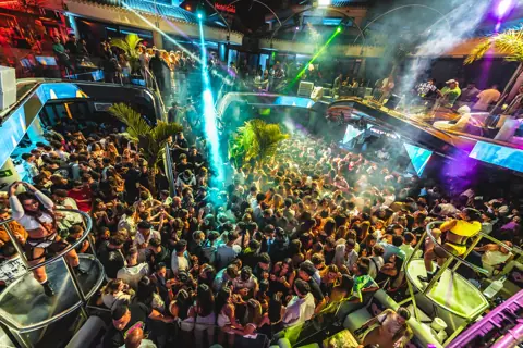 Vista cenital de la pista abarrotada con láseres verdes y bailarinas en podios. Papagayo Beach Club, Tenerife, marzo 2024