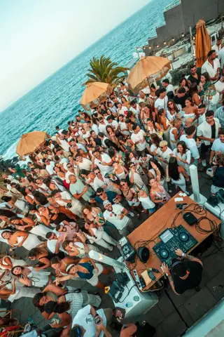 Público vestido de blanco baila en una terraza junto al mar. Noor (Riela), Tenerife, agosto 2025
