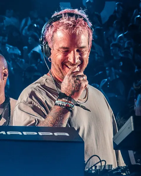 Luciano laughing at the booth in headphones, blue light, crowd behind. MAPPA 07 (Trilogy III), Tenerife, September 2026. Photo for Just Music.